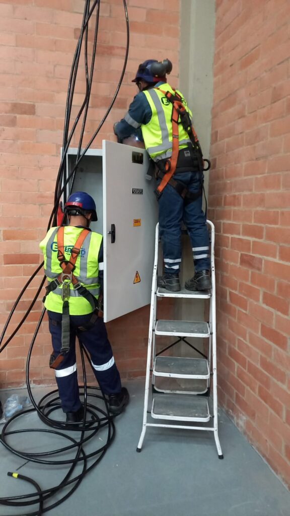 Equipo técnico realizando conexión y revisión de cableado eléctrico en gabinete industrial.