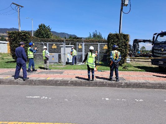 Personal técnico inspeccionando infraestructura eléctrica exterior en zona de subestación.