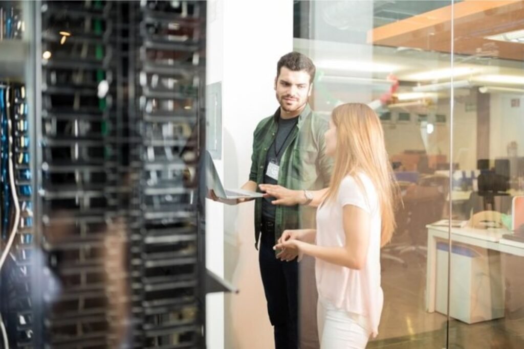 Dos personas revisando un rack de comunicaciones abierto en una oficina