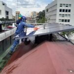 Operario fijando un panel solar sobre una cubierta industrial