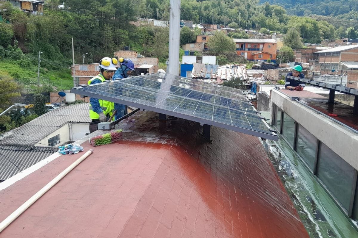 Operarios trabajando sobre una cubierta con paneles solares instalados