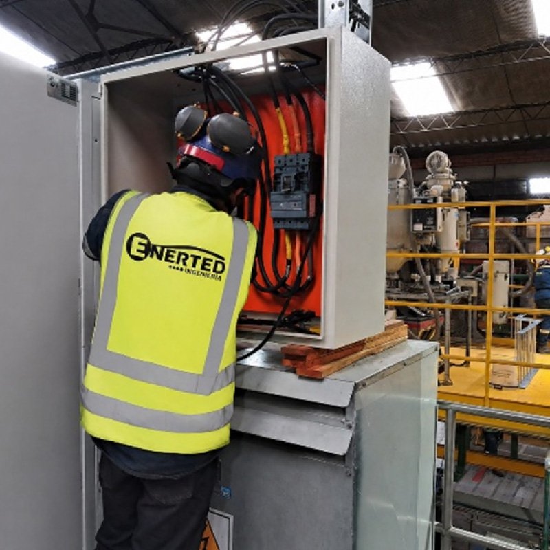 Técnico de Enerted con equipo de protección interviniendo un tablero en planta