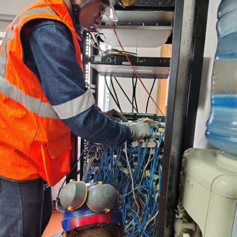 Técnico organizando el cableado de un rack de comunicaciones