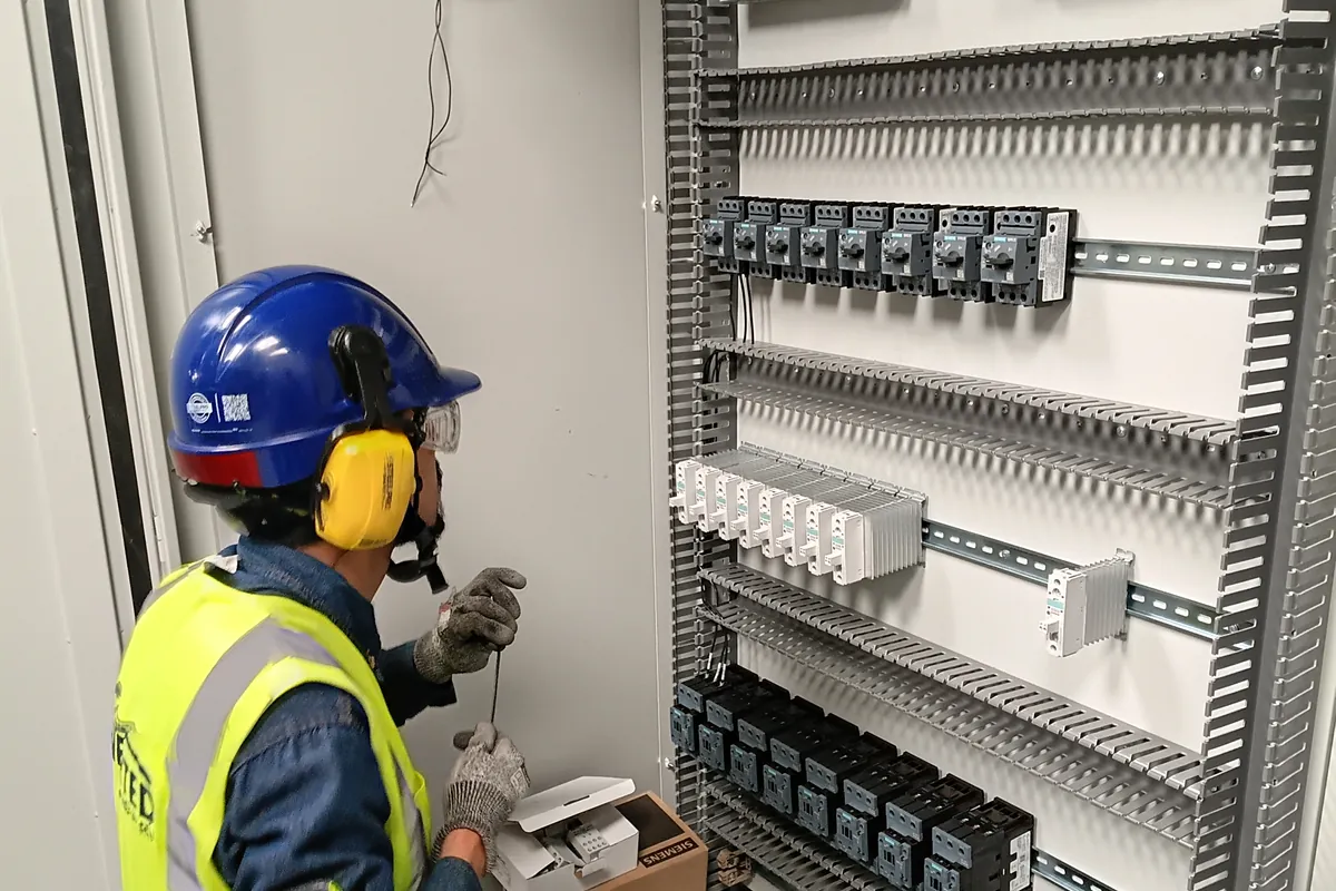 Técnico de Enerted montando componentes en un tablero de control industrial