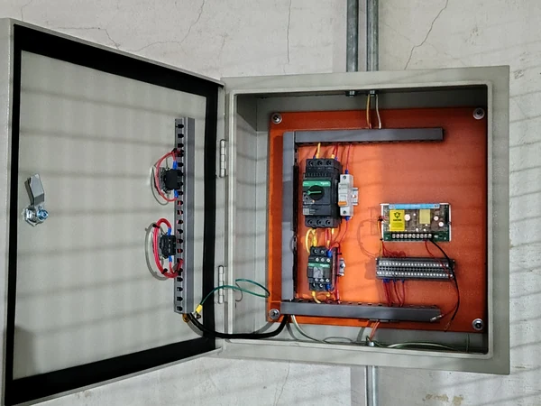 Tablero de control industrial abierto con PLC y borneras cableadas