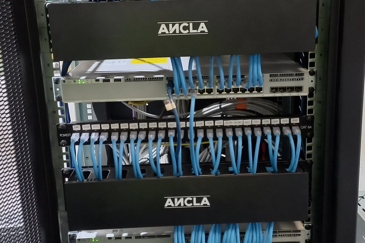 Rack de comunicaciones organizado por Enerted con patch cords azules y patch panels identificados